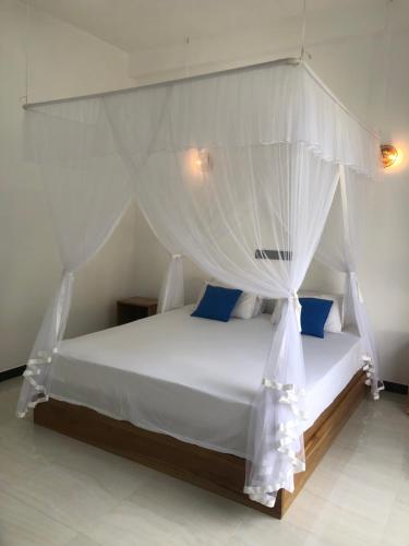 a bedroom with a white bed with a canopy at La Casa Mirissa in Mirissa