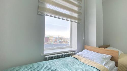 a bedroom with a bed and a large window at Sayak hostel in Karakol