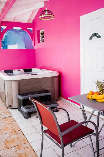 une cuisine avec des murs roses, une table et des chaises dans l'établissement Domaine de la rosa spa privatif, à Les Abymes