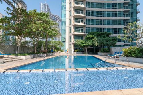 a swimming pool in a city with a tall building at Vacay Lettings - Loft Downtown Dubai in Dubai