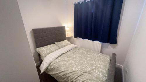 a small bedroom with a bed with a blue curtain at Cosy 4 bedroom holiday let Stevenage 22mins from London on the train in Stevenage
