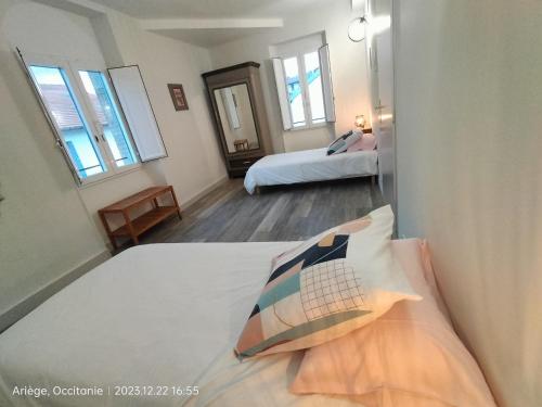 a bedroom with two beds and two windows at L'école buissonnière in Laroque-dʼOlmes