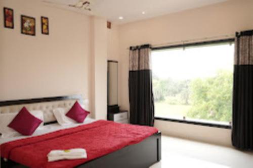 een slaapkamer met een rood bed en een groot raam bij Hotel Seven View Durg in Durg