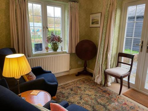 a living room with a couch and a chair and windows at The Coach House in Rudgwick