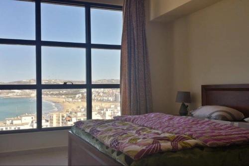 een slaapkamer met een bed en een groot raam bij Newcenter Suites in Tanger
