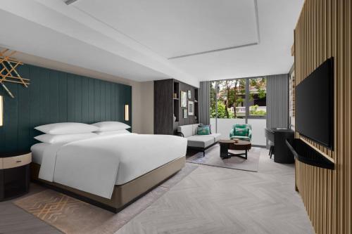 a bedroom with a large white bed and a living room at Madi Paidi Bangkok, Autograph Collection in Bangkok