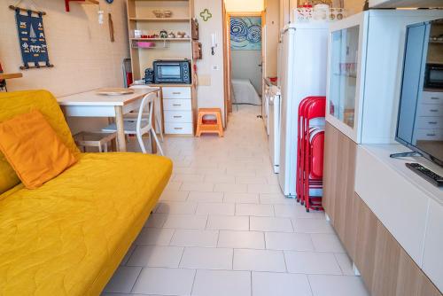 uma sala de estar com um sofá amarelo e uma cozinha em SE031 - Senigallia, bilocale fronte mare al residence Piramidi em Scapezzano