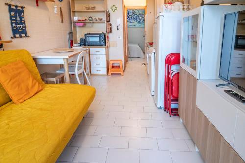 a living room with a yellow couch and a kitchen at SE031 - Senigallia, bilocale fronte mare al residence Piramidi in Scapezzano