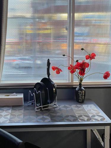 a window sill with a table and a vase with red flowers at Tomi Home 2F in Tokyo
