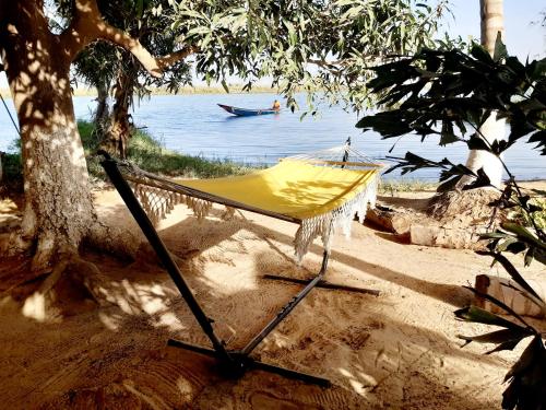 a hammock on a beach with a boat in the water at Mon paradis in Saint-Louis