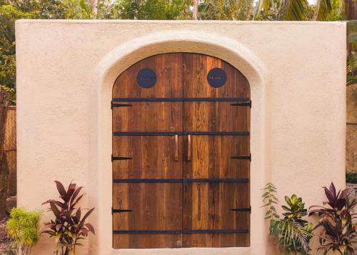 a wooden door in a wall with an arch at Firesky Glamping Ocam Ocam Beach in New Busuanga