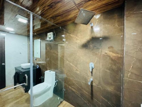 a bathroom with a toilet and a glass shower door at Kadwali Villa with Private Pool in Ujjain