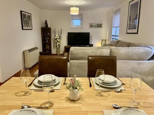 a living room with a table with plates and wine glasses at La Scala Inverness City Apartment in Inverness
