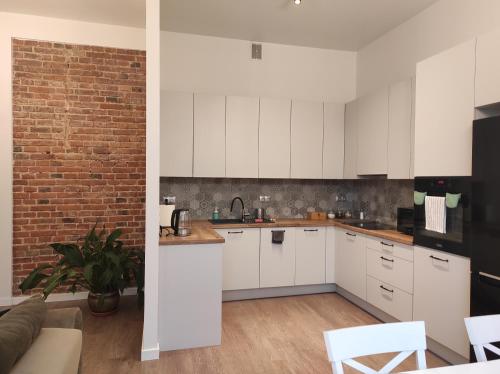 uma cozinha com armários brancos e uma parede de tijolos em Chabrowy - Apartamenty Smart Projekt em Tarnów