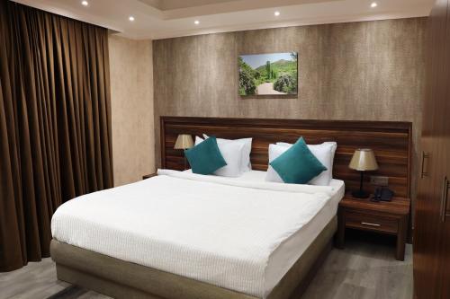 a bedroom with a large white bed with green pillows at Korek Mountain Resort in Erbil
