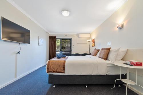 a bedroom with a large bed and a tv at Econo Lodge Rivervale in Perth