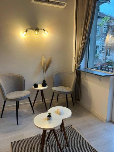 a living room with chairs and tables and a window at Pirostka Vintage Room in Sofia
