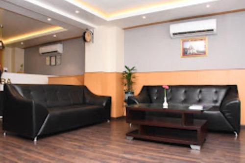 Hotel Yaiphabaa , Imphal في امفال: غرفة معيشة مع أريكة جلدية سوداء وطاولة