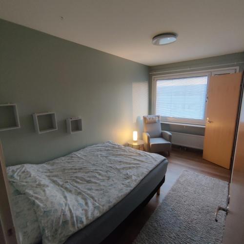 ein Schlafzimmer mit einem Bett, einem Stuhl und einem Fenster in der Unterkunft GREEN in Närpiö