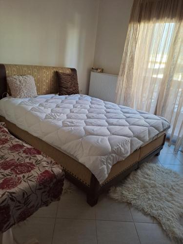 - un grand lit installé dans une chambre à côté d'une fenêtre dans l'établissement Hera Apartment, à Alexandroúpolis