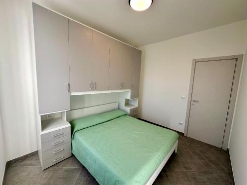 Schlafzimmer mit einem grünen Bett und weißen Schränken in der Unterkunft Casa Maestrale - Elegante con Balcone Vista Mare in Finale Ligure