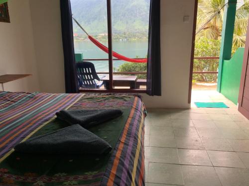 a bedroom with a bed and a large window with a view at Mario Lakeside Apartments in Tuk Tuk