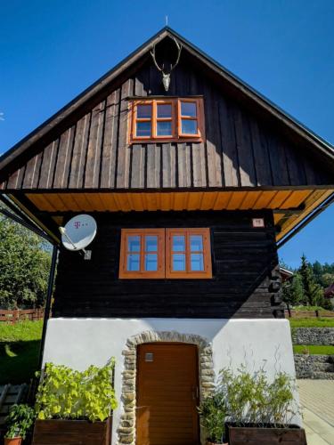 a black house with a gambrel roof and a door at Traditional deer Cabin with Sauna in Dolný Kubín