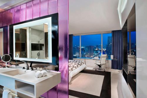 a bathroom with a sink and a large mirror at W Bangkok Hotel in Bangkok