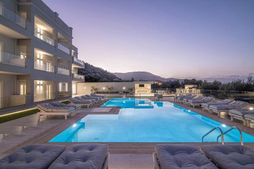 a large swimming pool with lounge chairs and a hotel at Filia Luxury Suites in Stalís