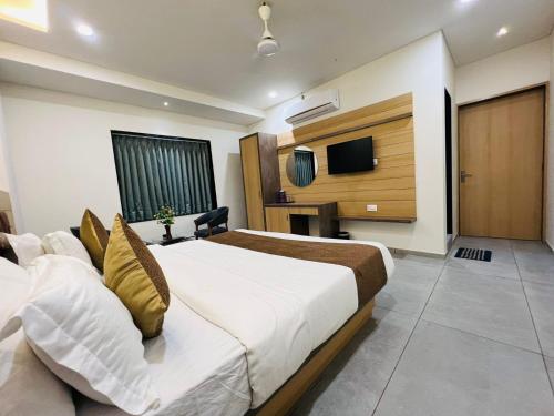 una camera d'albergo con letto e TV di Hotel Venus By Mantram Hospitality a Rajkot