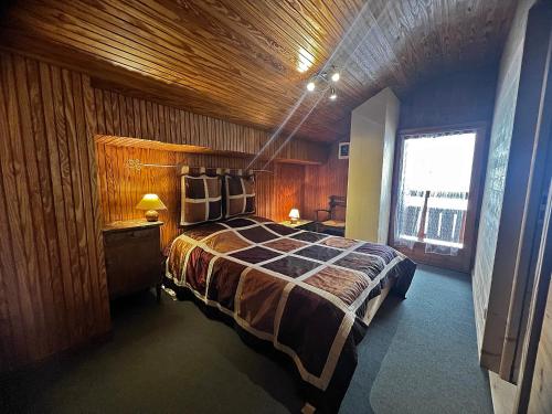 une chambre avec un grand lit avec un plafond en bois dans l'établissement Ty Menez 2 - Chalet sur les pistes, à La Clusaz
