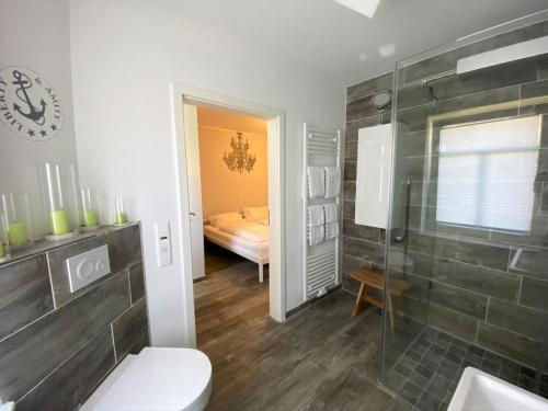 a bathroom with a toilet and a shower and a bedroom at FriesenART in Norddeich
