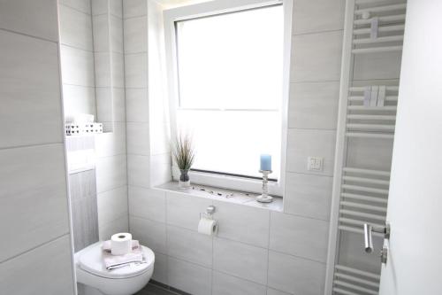 bagno bianco con servizi igienici e finestra di EigenTraum a Norddeich