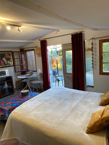 ein Schlafzimmer mit einem großen weißen Bett und einem Tisch in der Unterkunft Chalet des oliviers avec climatisation in Béziers