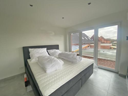 een slaapkamer met een bed met witte kussens en een raam bij Die Zimmerei 5 in Krummhörn