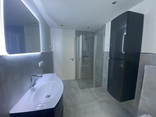 een badkamer met een witte wastafel en een douche bij Die Zimmerei 5 in Krummhörn
