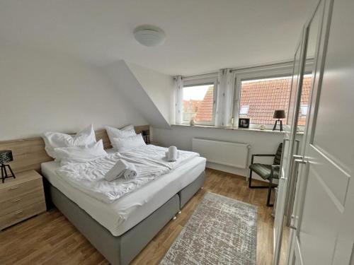 a white bedroom with a bed and a window at Deichblick 2 - Traumhaft am Deich in Norddeich
