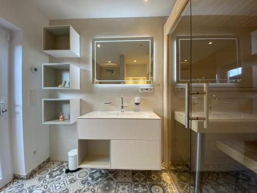 een badkamer met een wastafel en een glazen douche bij Wilde Brise - Ihr Luxusbungalow in Norddeich in Norddeich