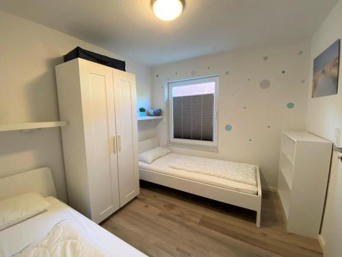ein kleines Schlafzimmer mit 2 Betten und einem Fenster in der Unterkunft Küstenoase - Norddeich Erholung in Bestlage in Norddeich