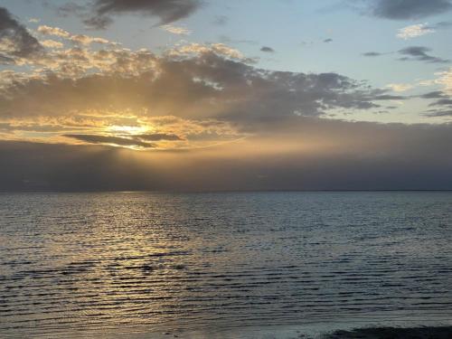 a sunset over the ocean with the sun setting at Wilde Brise - Ihr Luxusbungalow in Norddeich in Norddeich
