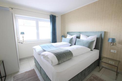Schlafzimmer mit einem großen weißen Bett und einem Fenster in der Unterkunft Seeblick 6 - Traumferien am Hafen in Norddeich
