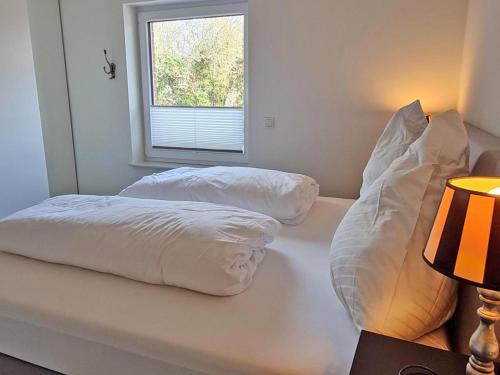 2 Kissen auf einem Bett in einem Zimmer mit Fenster in der Unterkunft Die Zimmerei 2 - Luxus in Greetsieler Toplage in Krummhörn