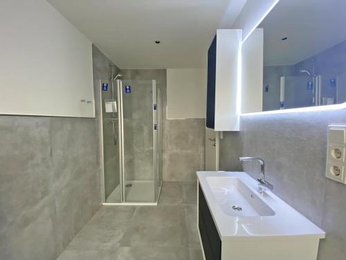 ein Bad mit einem Waschbecken und einer Dusche in der Unterkunft Die Zimmerei 2 - Luxus in Greetsieler Toplage in Krummhörn