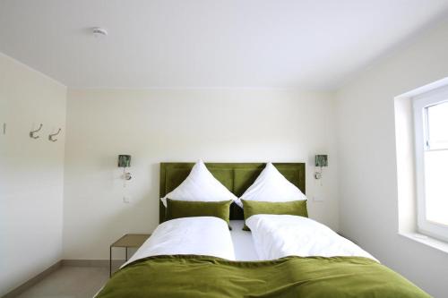 una camera da letto con un letto con cuscini verdi e bianchi di Seeblick 1 a Norddeich