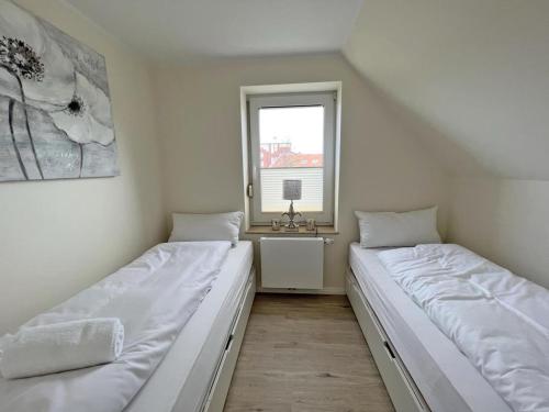 two beds in a room with a window at Deichblick 5 in Norddeich- Urlaub und Meerblick in Norden