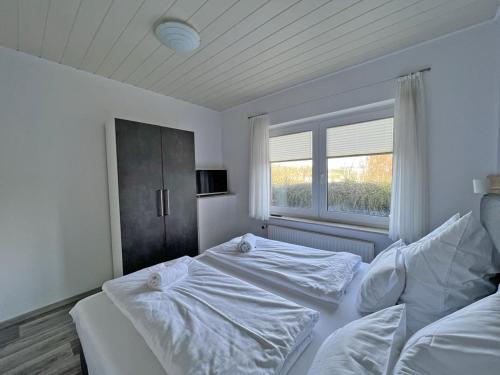 ein weißes Schlafzimmer mit einem Bett und einem Fenster in der Unterkunft Deichblick 4 in Norddeich- Urlaub und Erholung am Strand in Norden