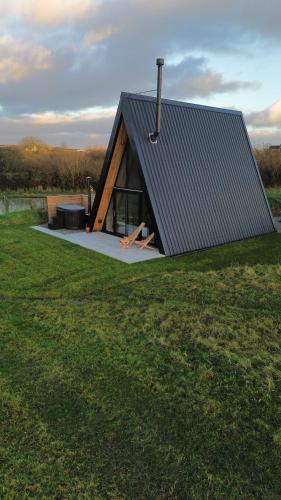 a small cabin with a roof on a grass field at Wilder Retreats - A Frame Cabins in Haverfordwest