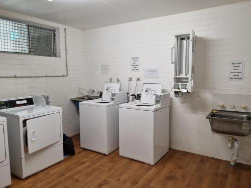 une chambre avec 4 lave-linge et sèche-linge ainsi qu'un lavabo dans l'établissement Seashell Studios Mandurah, à Mandurah