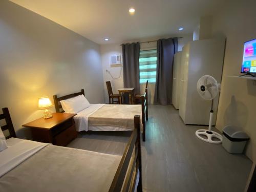 ABE Lodge Taguig في مانيلا: غرفة فندقية بسريرين وطاولة بها مصباح