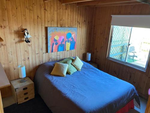 a bedroom with a blue bed in a wooden room at VISTA MAR casa familiar para 8 personas in Pichilemu